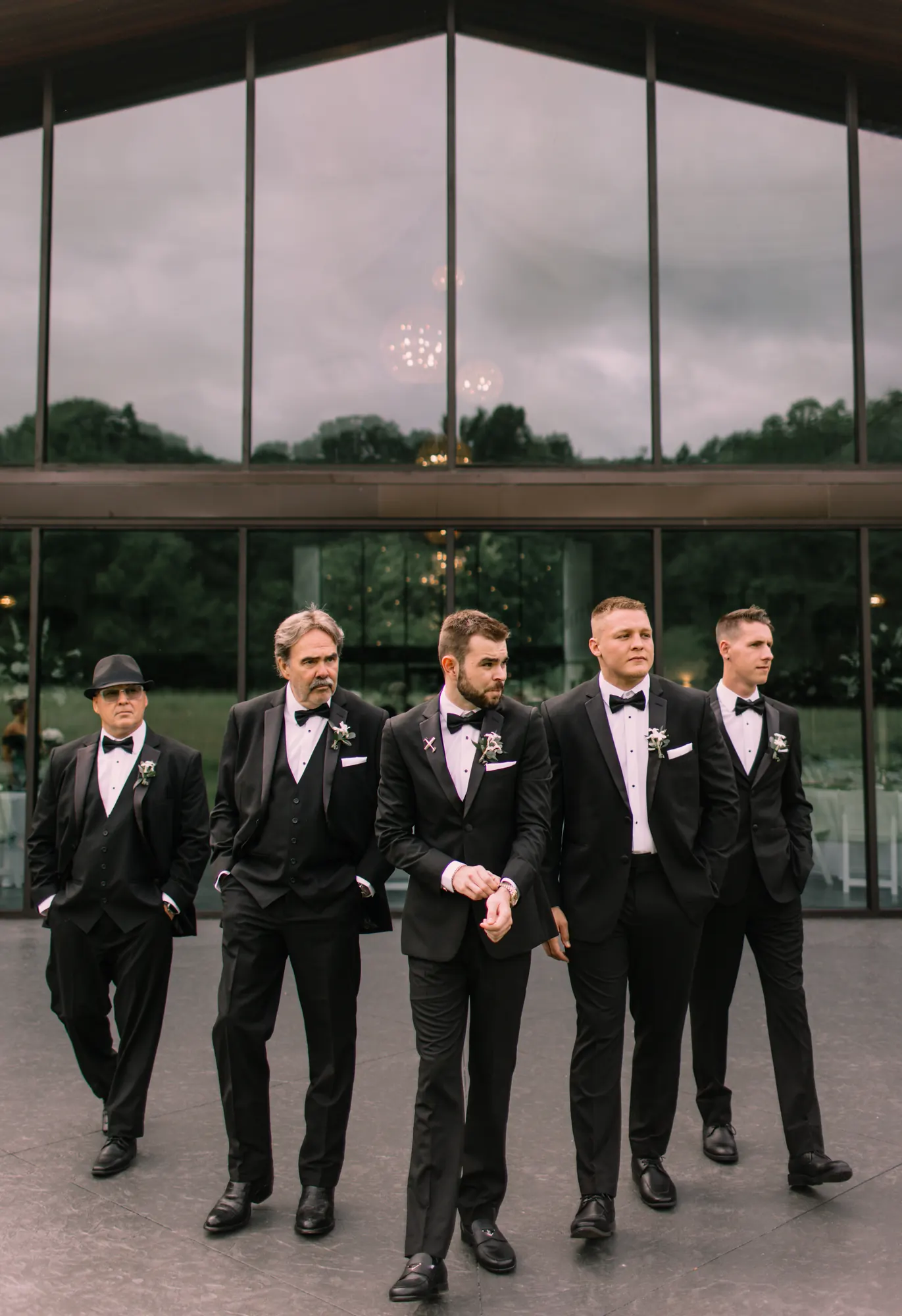 Five groomsmen in tuxedos walking together