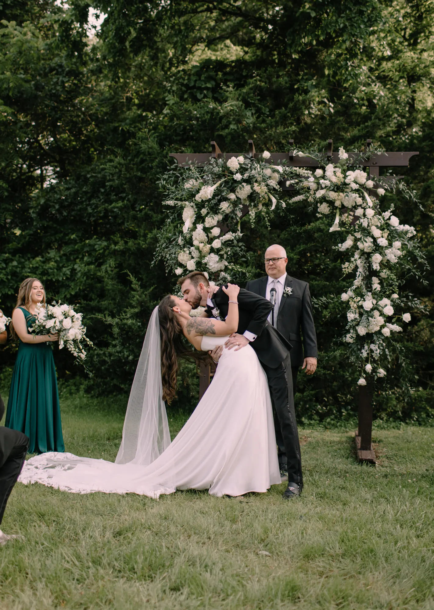 A bride and groom kissing under a floral arch