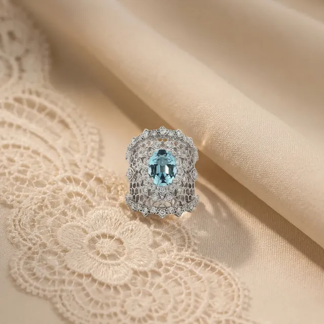 A white gold ring with a pale blue stone on lace