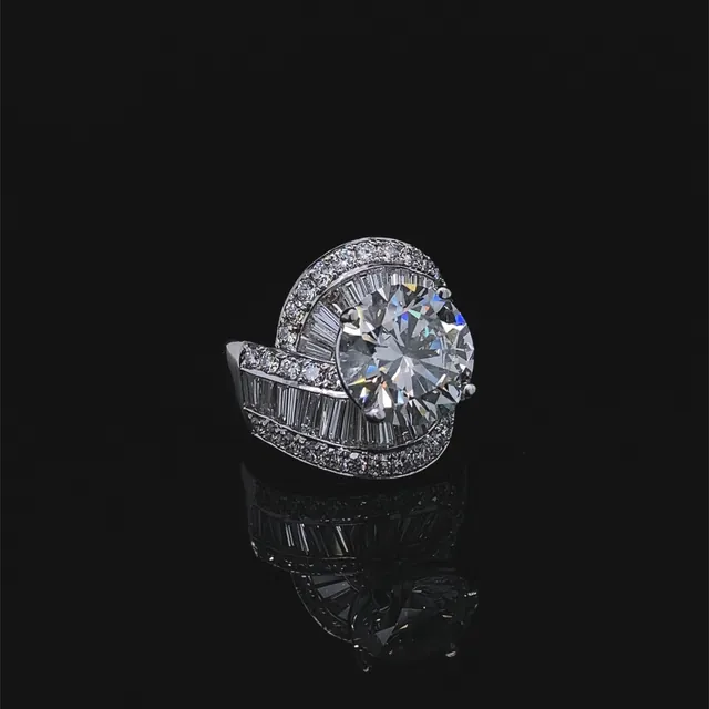 A round diamond ring with a swirl of baguette diamonds in white gold