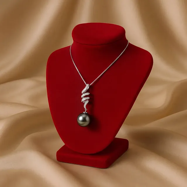 A dark pearl pendant on a red velvet bust