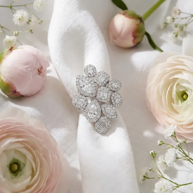 A white gold diamond flower cluster ring on white linen