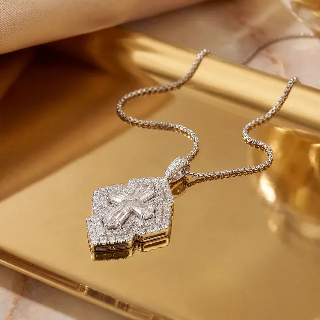A white gold diamond pendant on a gold tray