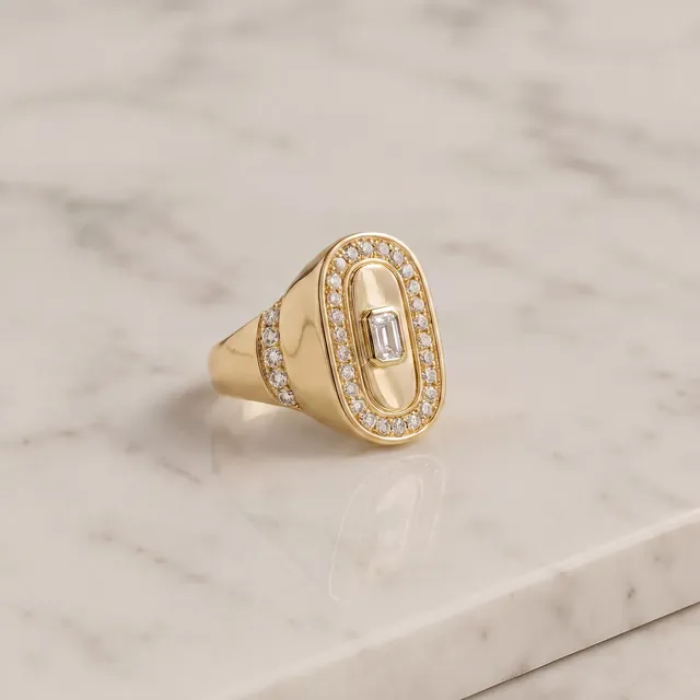 A yellow gold signet ring with an emerald cut diamond on marble