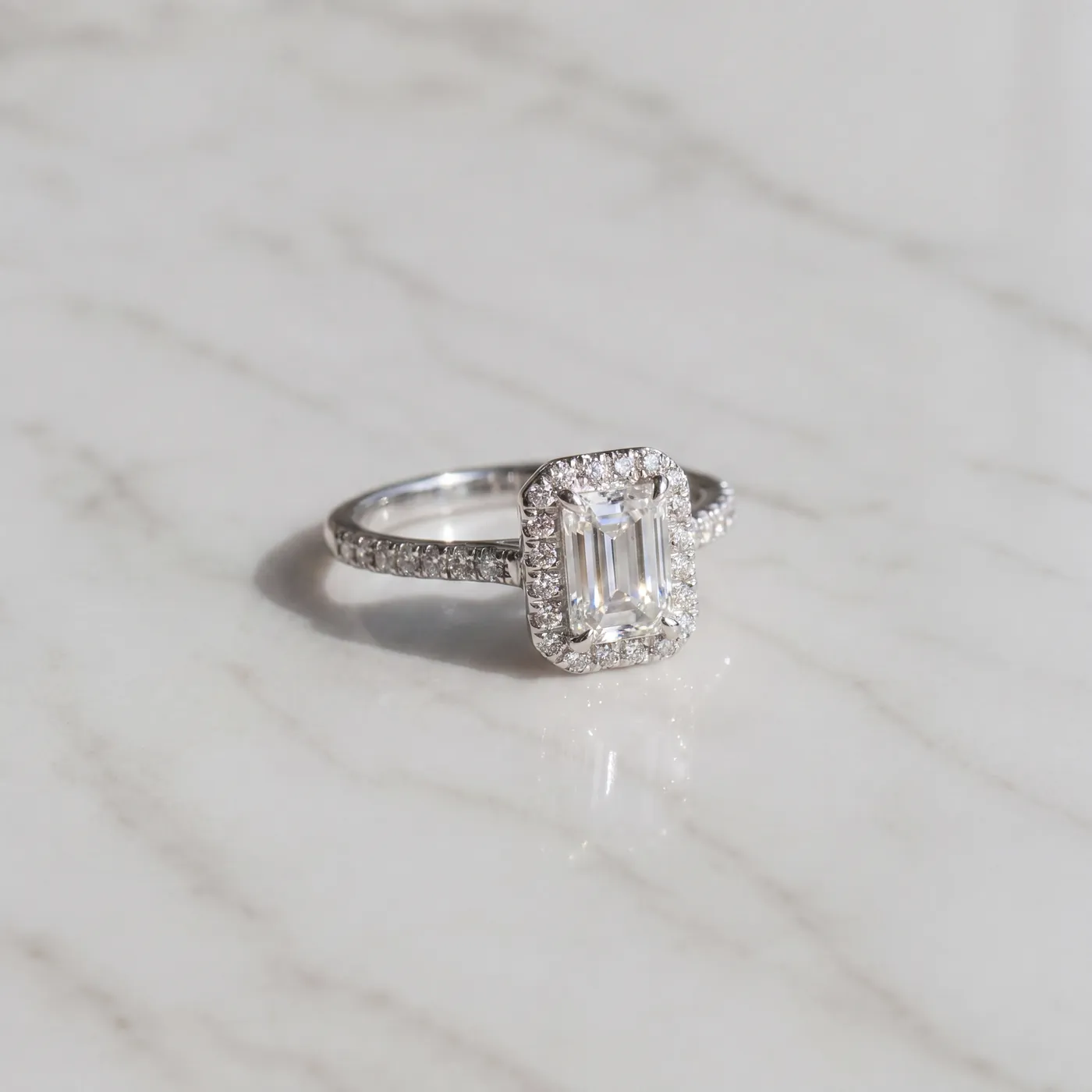 An emerald cut diamond solitaire on white marble