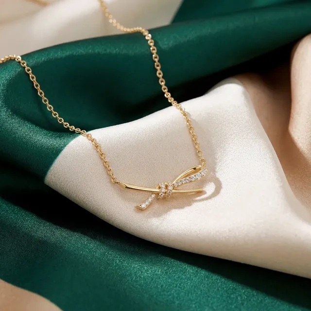 A fine gold necklace with a small bow on green and ivory silk