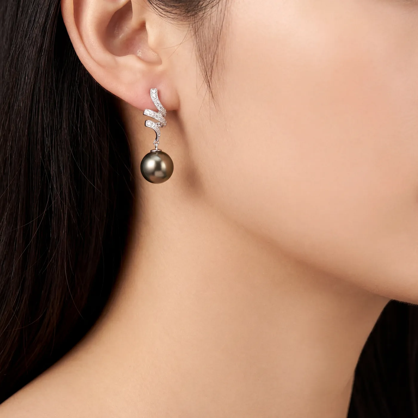 A woman wearing a pearl and diamond drop earring