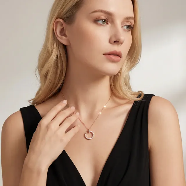 A woman in a black dress wearing a fine gold pendant