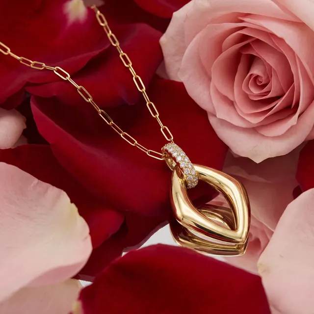A gold open marquise pendant among rose petals