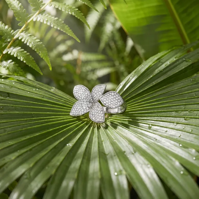 A white gold diamond orchid ring on a palm leaf