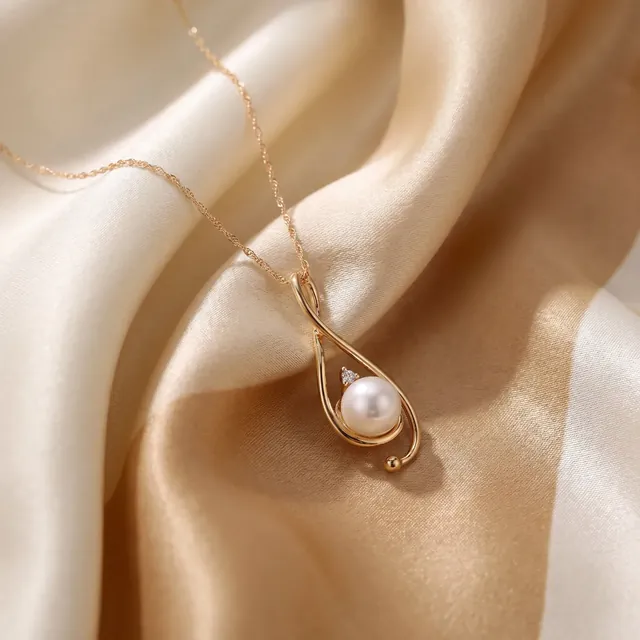 A gold loop pendant holding a pearl on cream satin