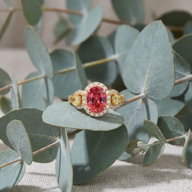 A pink and yellow three stone ring on eucalyptus leaves