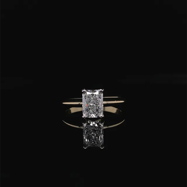 An elongated radiant cut diamond solitaire on a thin yellow gold band