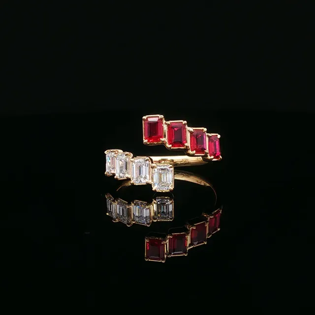 A yellow gold bypass ring with rubies and diamonds on black