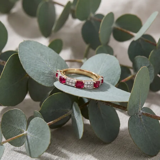 A yellow gold band of rubies and diamonds on eucalyptus