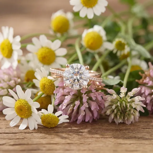 A rose gold round diamond ring among daisies and clover