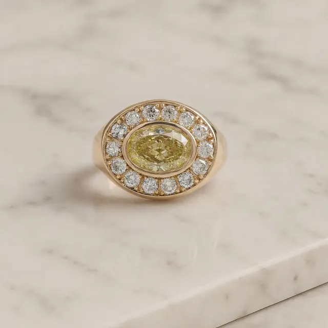A yellow gold oval halo ring on marble